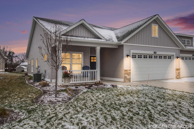 view of front of house with a garage, a lawn, central air condition unit, and a porch