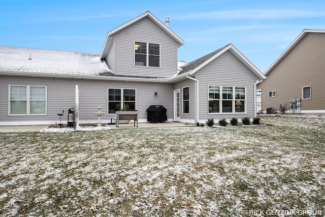 snow covered back of property with a patio, a yard, and central air condition unit