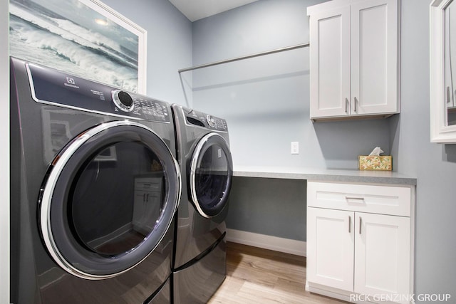 clothes washing area with cabinets, separate washer and dryer, and light hardwood / wood-style flooring