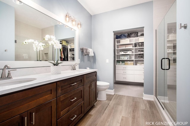 bathroom with hardwood / wood-style flooring, vanity, toilet, and an enclosed shower