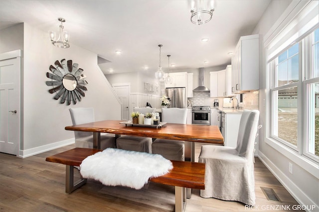 dining area with an inviting chandelier, plenty of natural light, light hardwood / wood-style floors, and sink