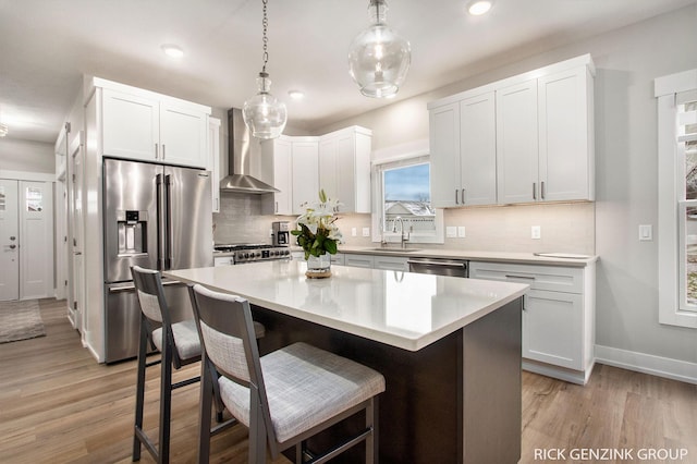 kitchen featuring white cabinetry, stainless steel appliances, and wall chimney exhaust hood