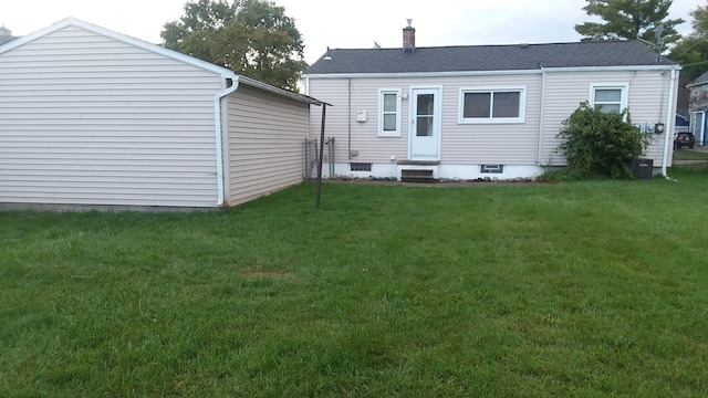 rear view of house featuring entry steps, a yard, a chimney, and central AC unit