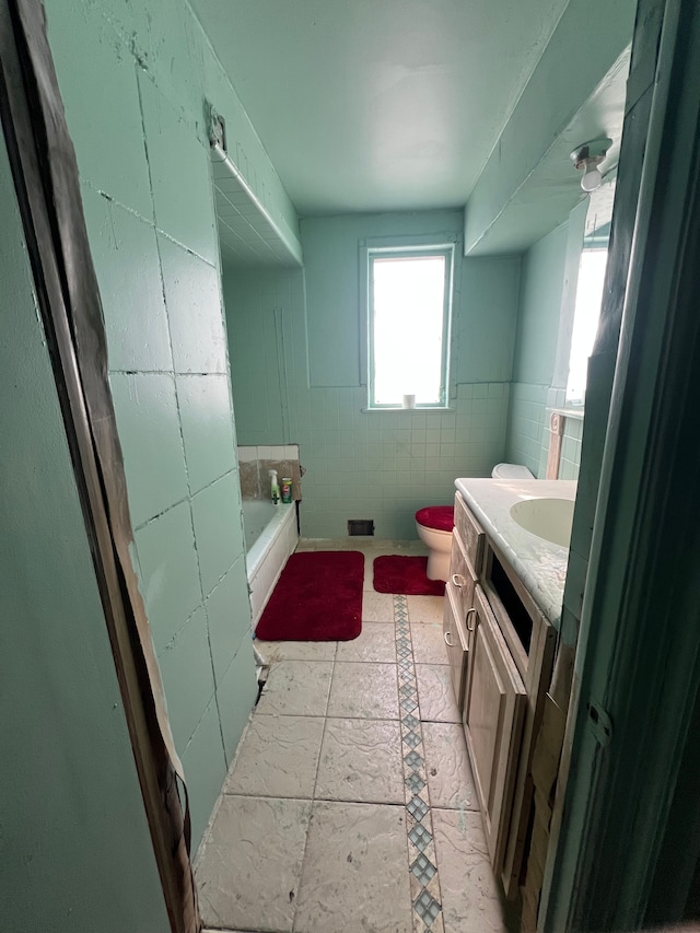 bathroom with vanity, a washtub, tile walls, and toilet