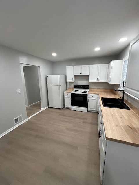 kitchen featuring sink, white refrigerator, electric stove, hardwood / wood-style floors, and white cabinets