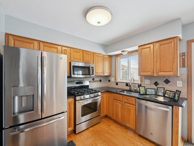 kitchen with sink, backsplash, appliances with stainless steel finishes, and light wood-type flooring