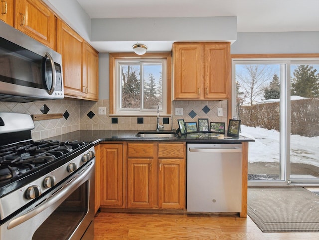 kitchen featuring appliances with stainless steel finishes, sink, light hardwood / wood-style floors, and backsplash