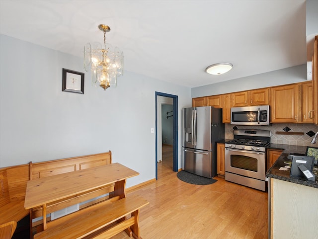 kitchen featuring light hardwood / wood-style flooring, a chandelier, stainless steel appliances, hanging light fixtures, and tasteful backsplash