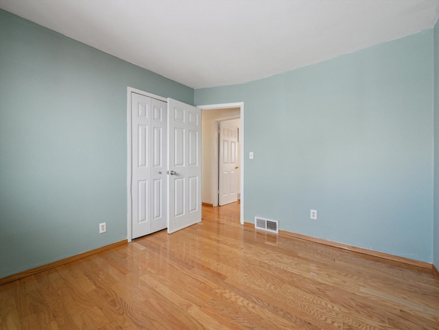 unfurnished bedroom with light wood-type flooring and a closet