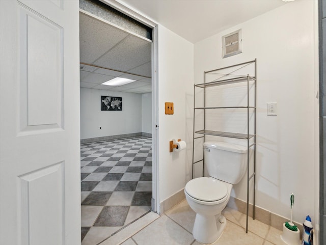 bathroom with toilet and a drop ceiling