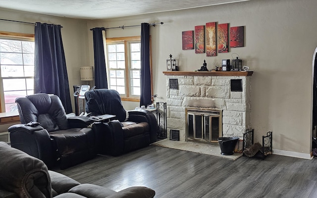 living room featuring wood-type flooring, a fireplace, and a textured ceiling