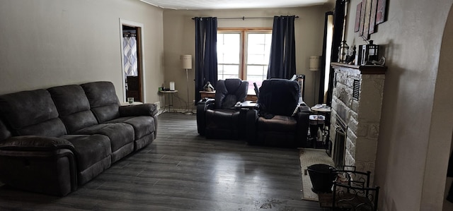 living room featuring dark hardwood / wood-style flooring and a stone fireplace