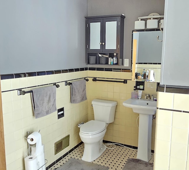 bathroom with tile walls, sink, and toilet