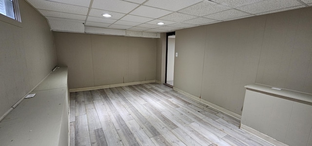 spare room with a paneled ceiling and light wood-type flooring