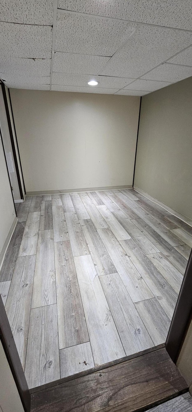 interior space featuring a drop ceiling and light wood-type flooring