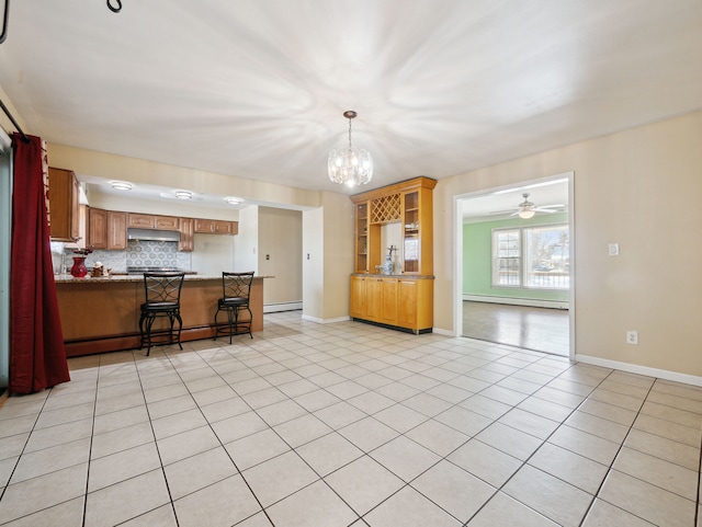 kitchen featuring a kitchen bar, a baseboard heating unit, light tile patterned floors, and kitchen peninsula