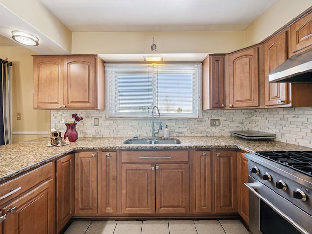 kitchen with light tile patterned floors, sink, high end stainless steel range oven, light stone counters, and decorative backsplash