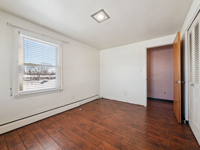 empty room with dark hardwood / wood-style floors and baseboard heating