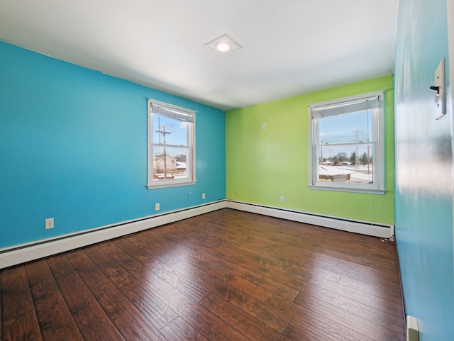 empty room with dark hardwood / wood-style floors and a baseboard heating unit