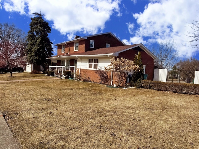 view of front of house with brick siding, covered porch, and a front lawn