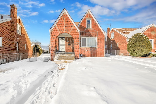 english style home featuring brick siding and fence