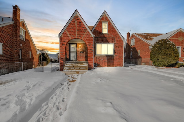 tudor home featuring brick siding and fence