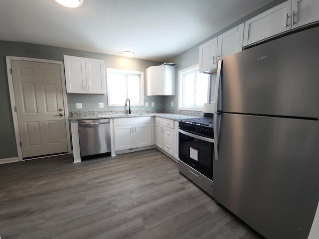 kitchen featuring sink, light stone counters, light wood-type flooring, appliances with stainless steel finishes, and white cabinets