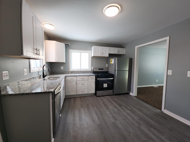 kitchen with white cabinetry, stainless steel appliances, sink, and dark stone counters