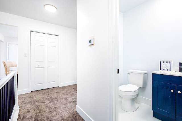 bathroom featuring toilet, baseboards, a closet, and vanity