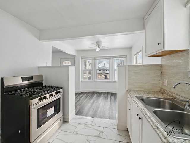 9941 Minock St, Detroit, MI 48228 - kitchen featuring sink, ceiling fan, stainless steel gas stove, white cabinetry, and backsplash