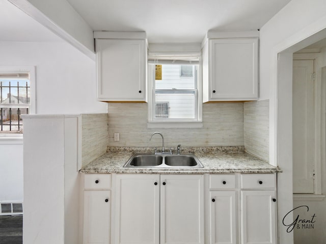 9941 Minock St, Detroit, MI 48228 - kitchen with white cabinetry, light stone countertops, sink, and tasteful backsplash