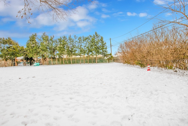 snowy yard featuring fence