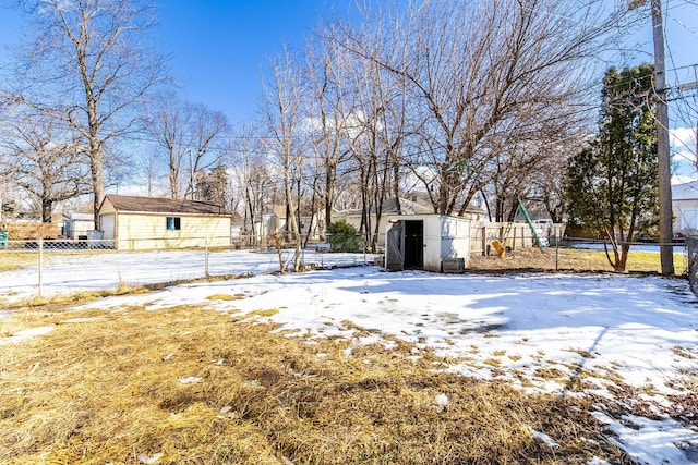 yard layered in snow featuring an outbuilding, fence, and a storage unit