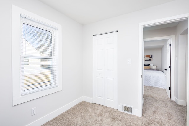 unfurnished bedroom with carpet floors, baseboards, and visible vents