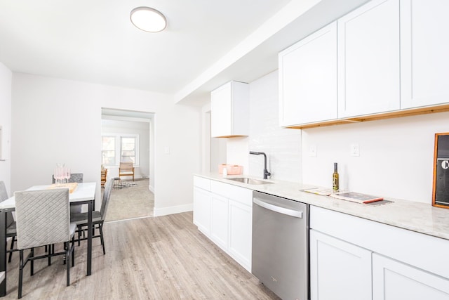 kitchen featuring light wood finished floors, stainless steel dishwasher, white cabinetry, a sink, and baseboards