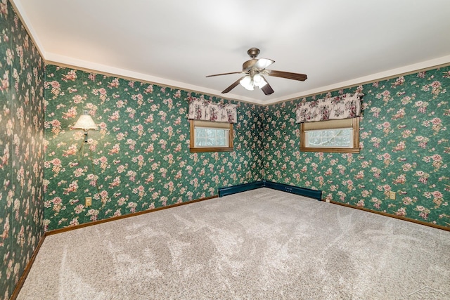 carpeted spare room with wallpapered walls, a ceiling fan, and baseboards