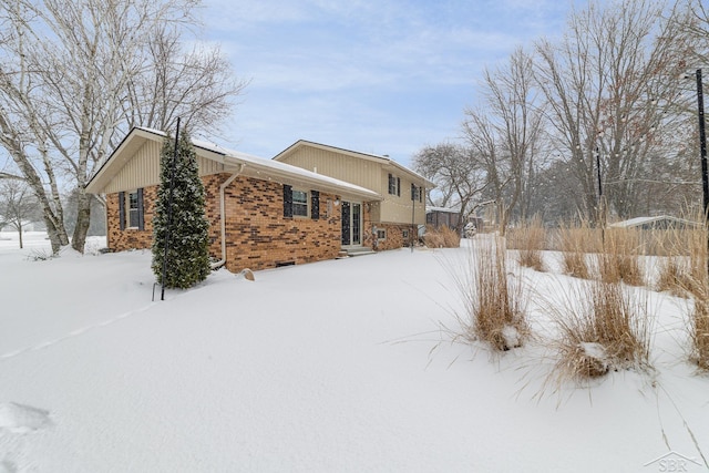 snow covered property with brick siding