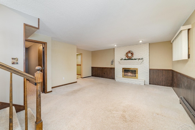 unfurnished living room featuring wainscoting, a brick fireplace, wood walls, and a baseboard radiator