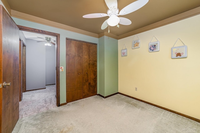 unfurnished bedroom featuring a ceiling fan, crown molding, carpet, and baseboards