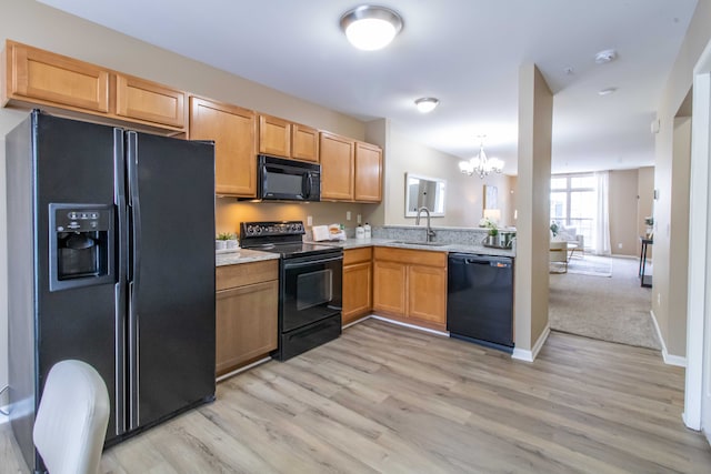 kitchen with light hardwood / wood-style flooring, sink, a chandelier, pendant lighting, and black appliances