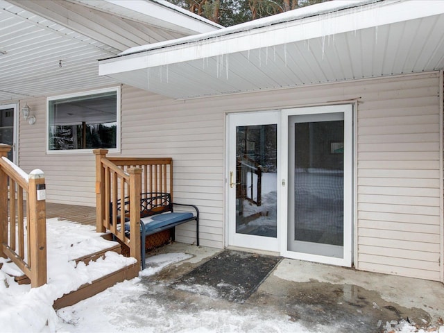 snow covered property entrance with a deck