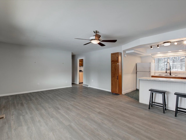 unfurnished living room featuring dark hardwood / wood-style flooring, ceiling fan, and sink