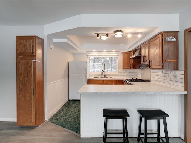 kitchen with sink, backsplash, a breakfast bar, white refrigerator, and stainless steel range oven