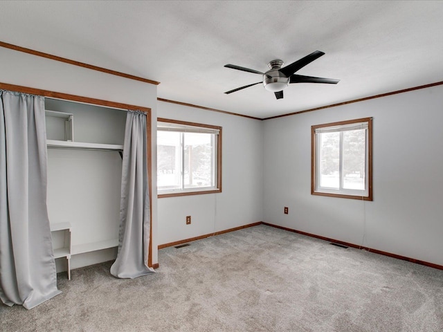 unfurnished bedroom featuring ornamental molding, light carpet, ceiling fan, and a closet