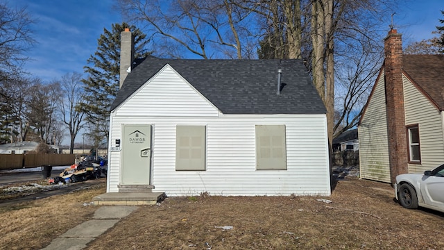 view of front of house with a shingled roof and a chimney