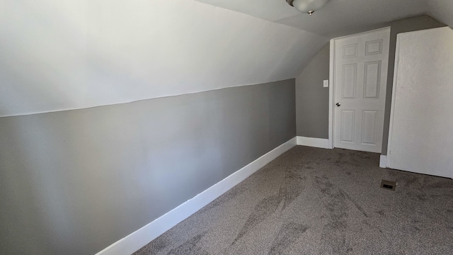 additional living space featuring carpet, baseboards, and vaulted ceiling