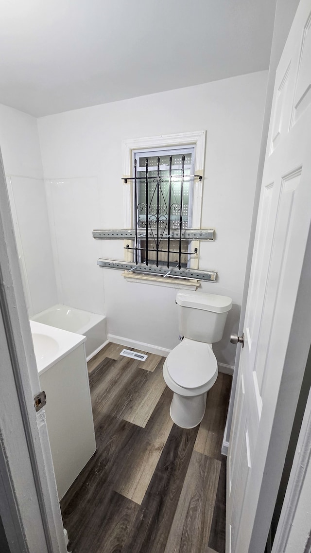 bathroom with toilet, wood finished floors, vanity, visible vents, and baseboards