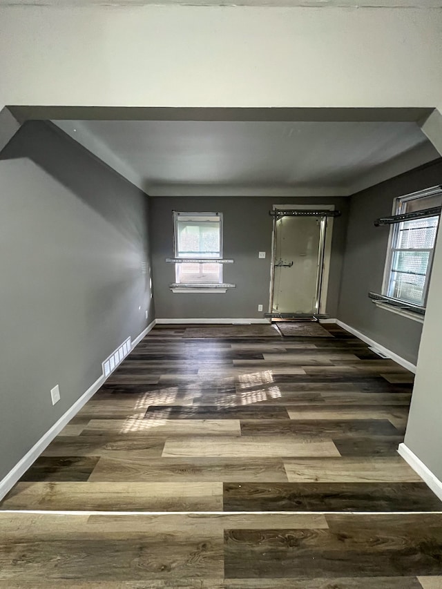 unfurnished room featuring visible vents, baseboards, and wood finished floors