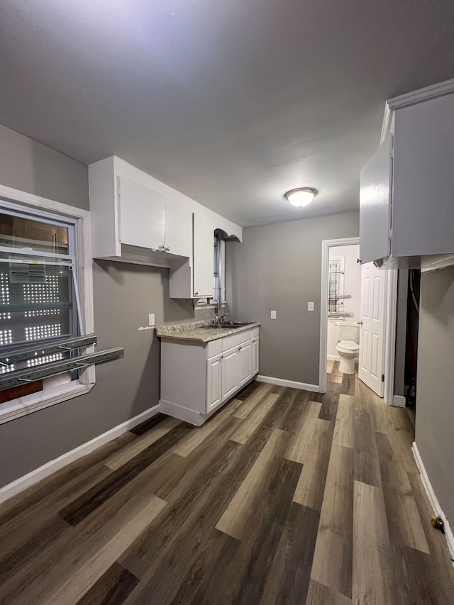 kitchen featuring dark wood-type flooring, white cabinetry, and baseboards