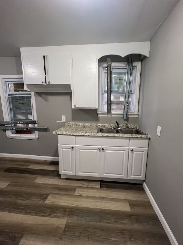 kitchen featuring dark wood-style floors, baseboards, white cabinets, and a sink